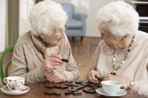 Two Senior Women Playing Dominoes At Day Care Centre